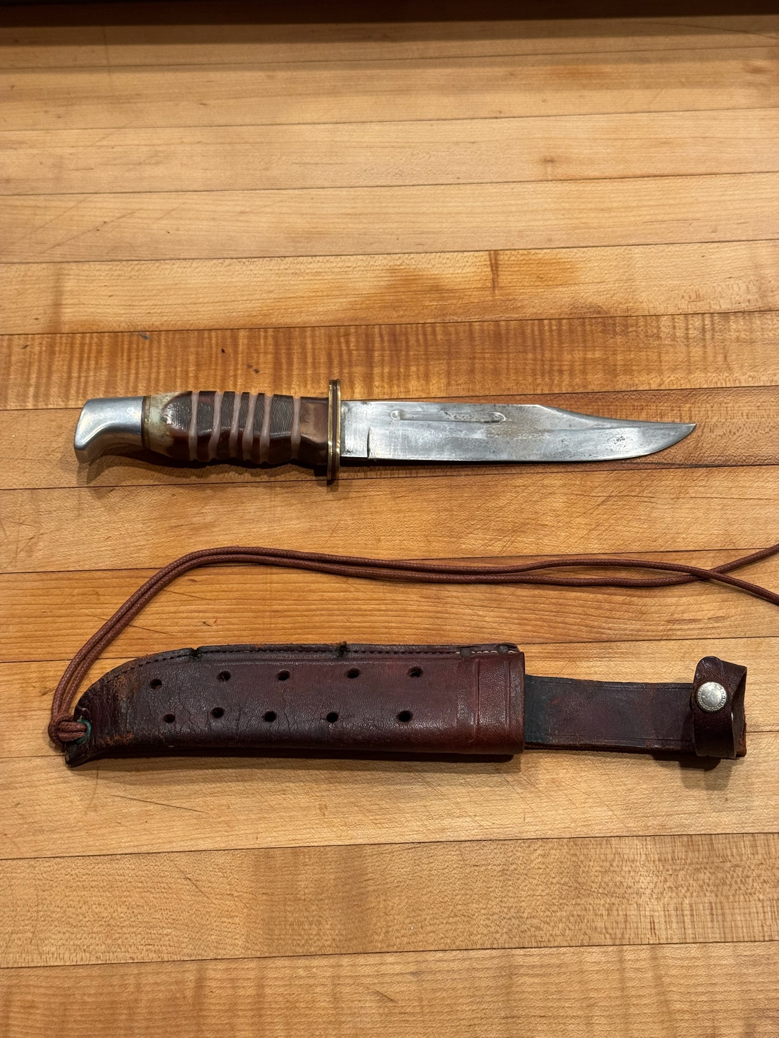 A fixed blade knife resting beside a leather sheath