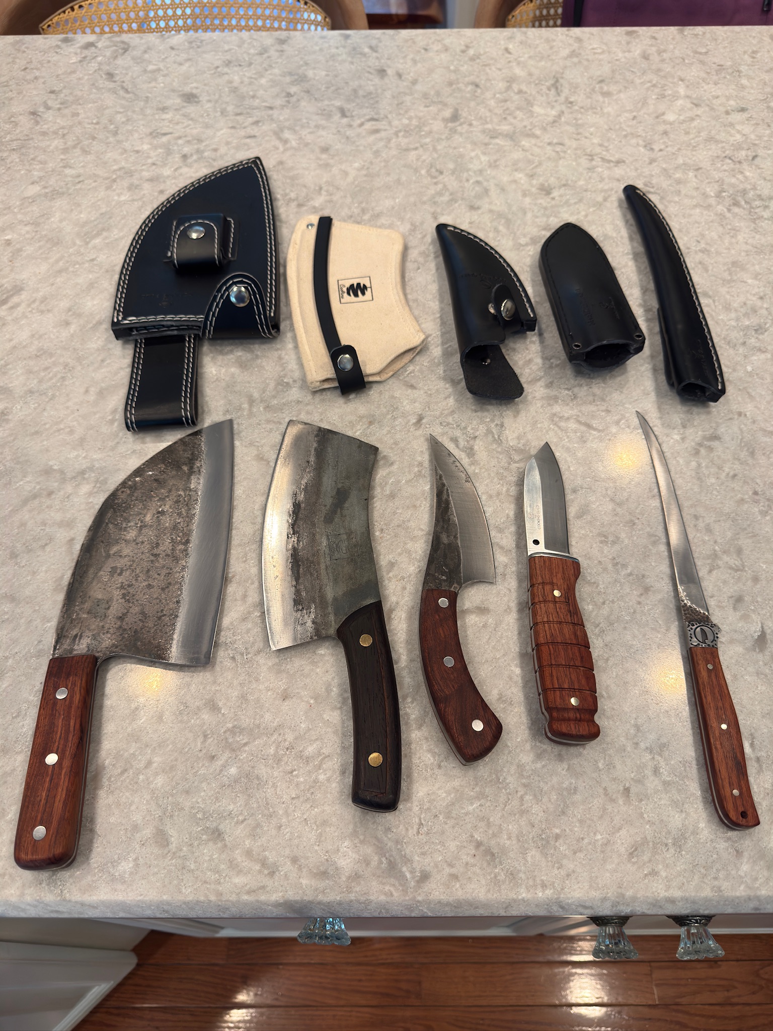 A range of knives and blades laid out on a workshop table